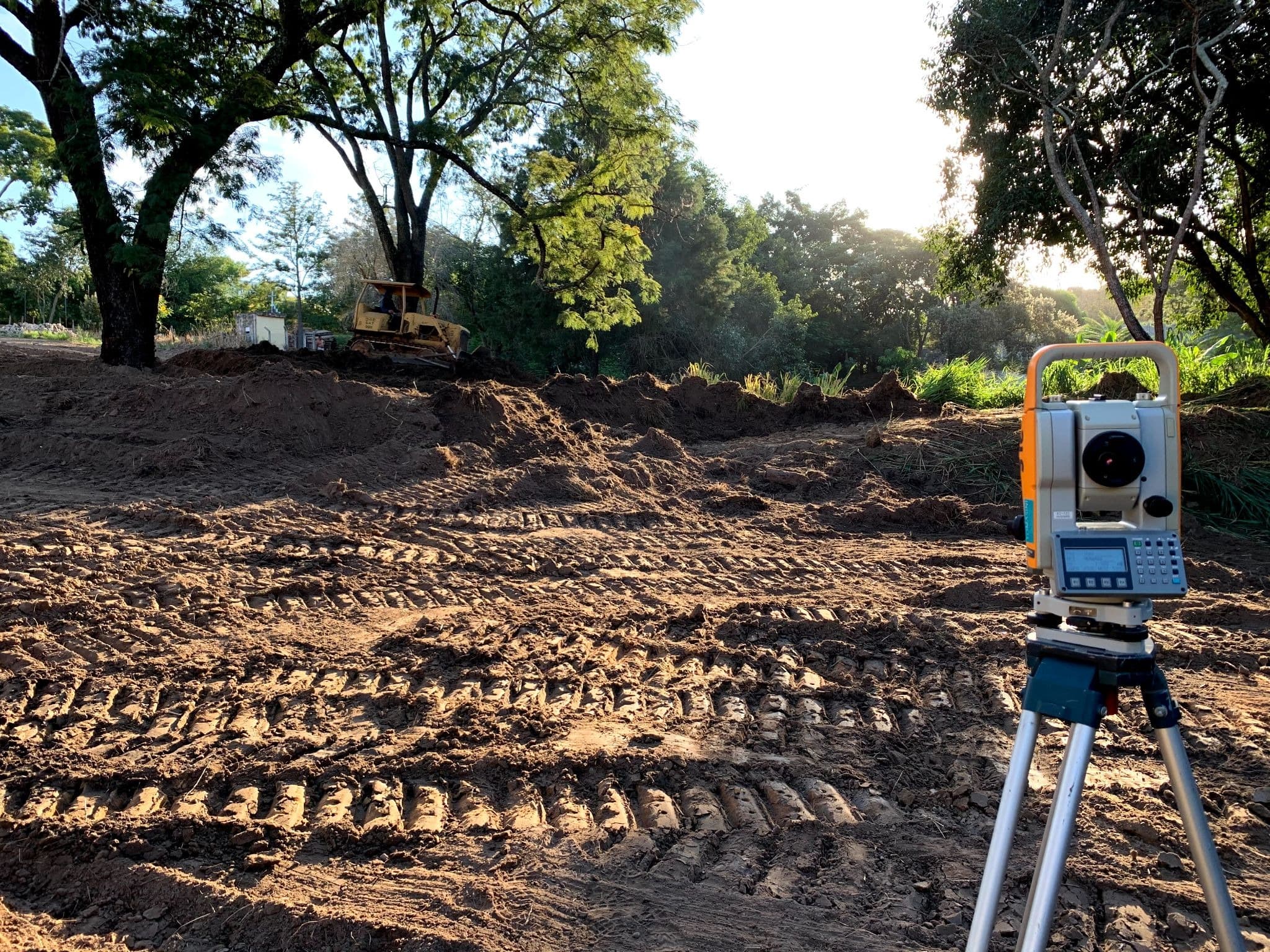 Equipamento topográfico posicionado em um terreno em preparação.