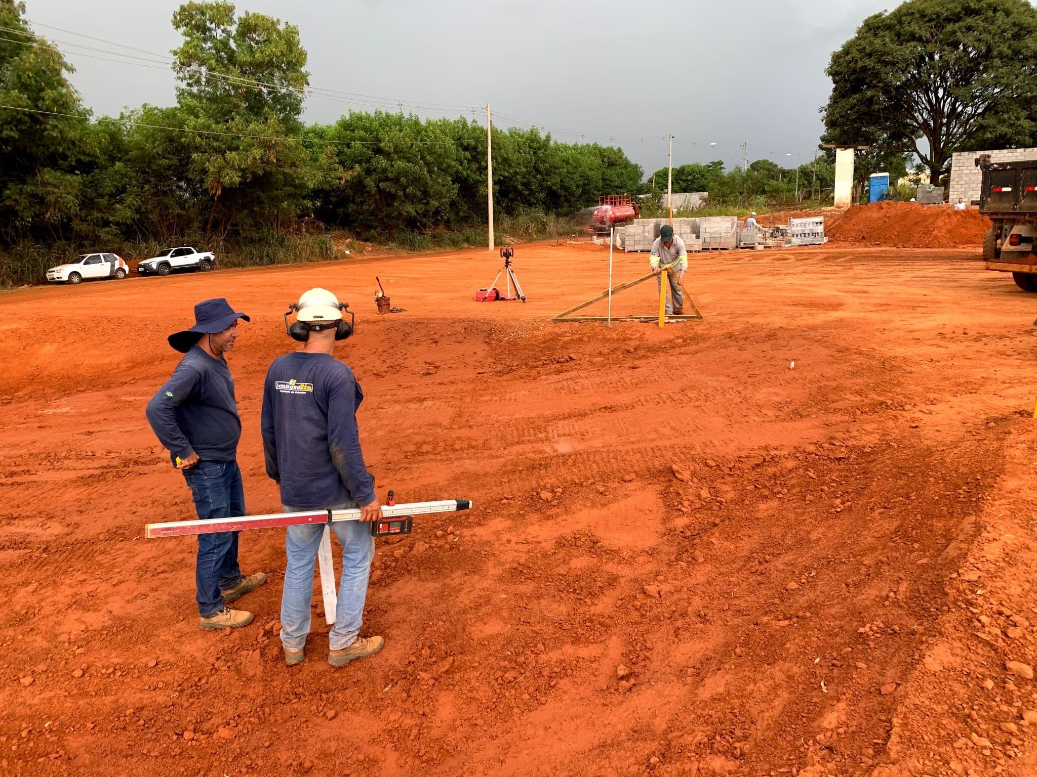 Equipe com equipamentos de topografia em uma área de terraplenagem.