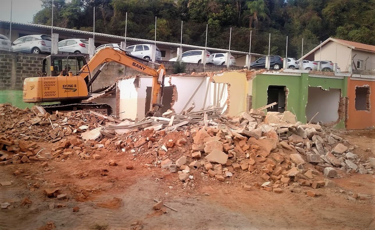 Escavadeira trabalhando na demolição de uma construção.